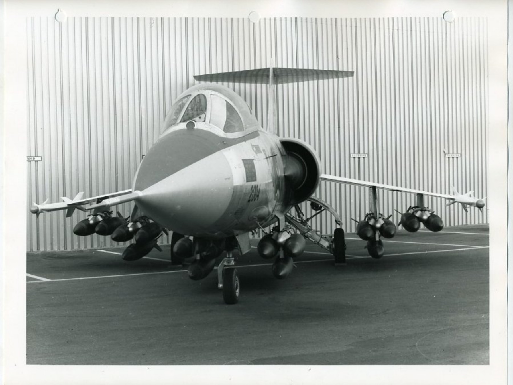 Schrägfrontansicht eines Lockheed-Mock-ups mit dicht angeordneten Bombenkörpern an Mehrfachträgern und schlanken Lasten an den Flügelspitzen.