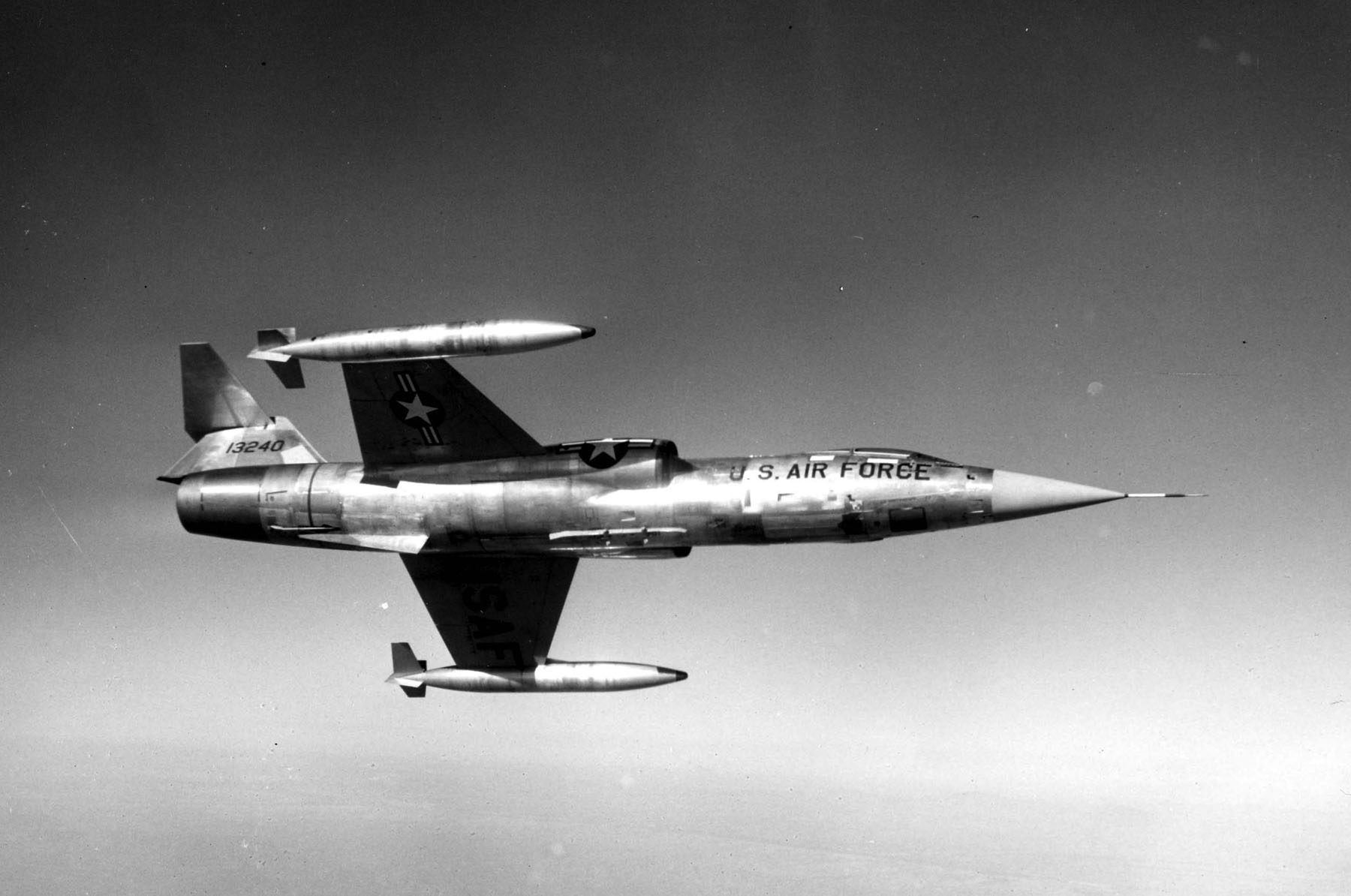 Eine für Deutschland gebaute F-104G im Flug, mit US-Air-Force-Kennzeichen und Tanks an den Flügelspitzen.